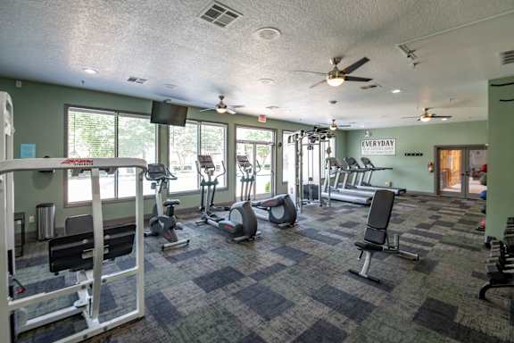 A gym with a variety of equipment including treadmills, weights, and exercise machines.