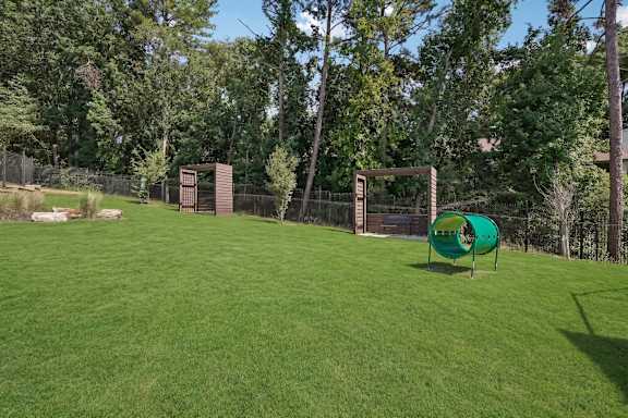 A green playground structure sits in a grassy field.