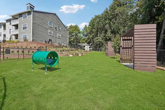 A playground with a green slide and a brown wooden structure.
