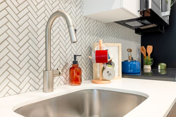 a kitchen sink with a silver faucet and a counter top with a bottle