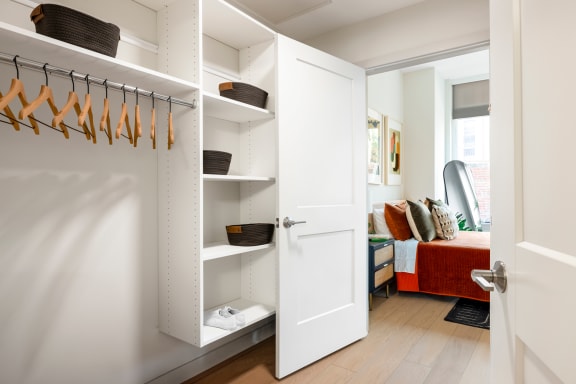 a closet with white closet doors and a white closet door with hangers