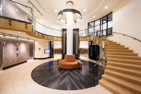 the lobby of a building with a staircase and a orange couch