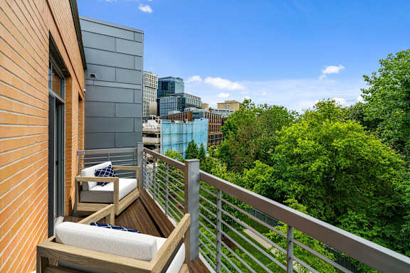 A balcony with a chair and a table overlooking a cityscape.