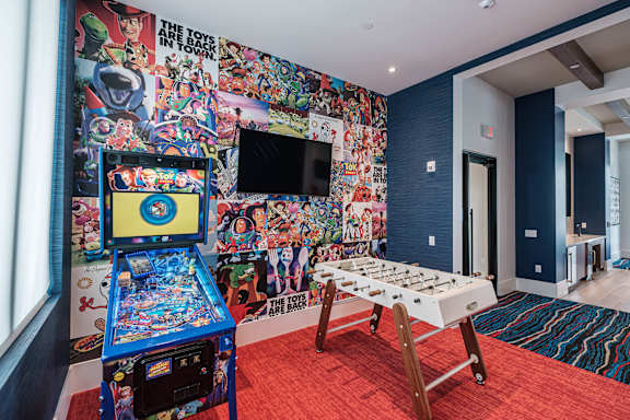 A room with a pinball machine and a foosball table.