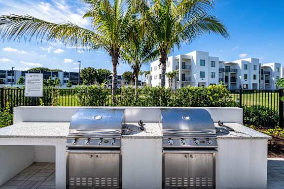Two built-in BBQ grills in a white outdoor kitchen.