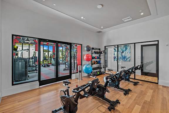 A gym with exercise bikes and a mirrored wall.