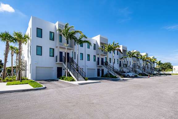 A white building with palm trees in front.