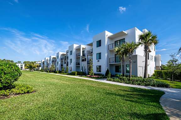 A row of white apartment buildings with green lawns in front.