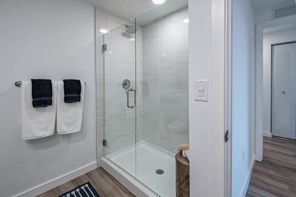 A bathroom with a glass shower stall and towel racks.