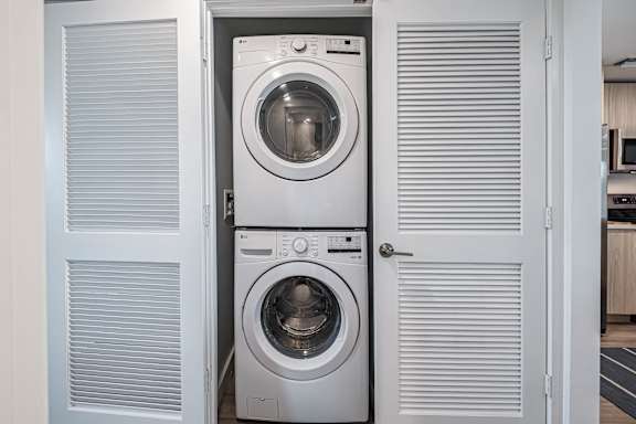 A white washing machine is in a cabinet with a door open.