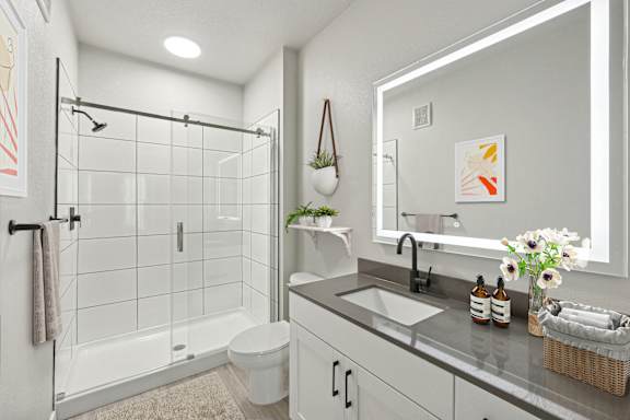 A bathroom with a white toilet, sink, and a glass shower stall.