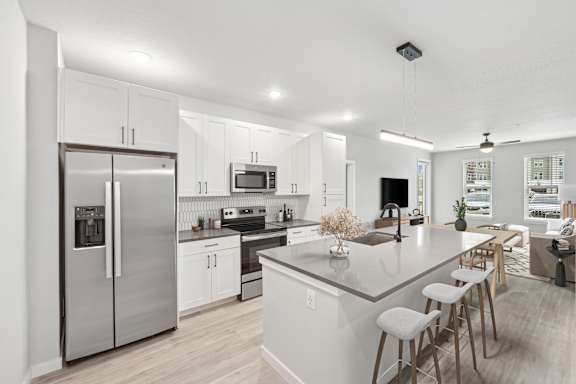 A modern kitchen with a refrigerator, microwave, oven, and sink.