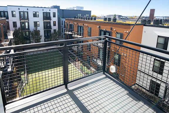 a private balcony with black railing and a city view