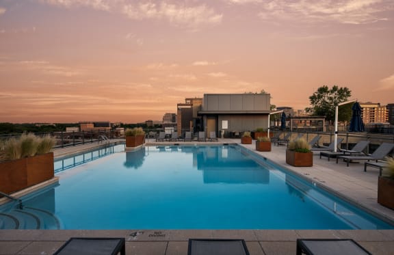 a rooftop pool with lounge chairs and a building in the background
