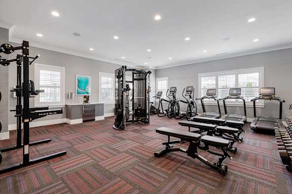 A gym with a variety of equipment including treadmills, weights, and exercise machines.