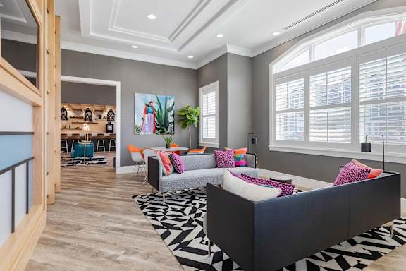 A living room with a black and white patterned rug and a grey couch.