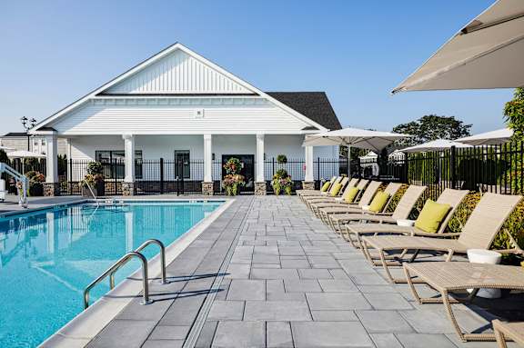 A pool area with sun loungers and a white building.