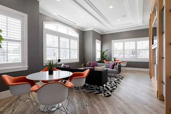 A modern dining room with a round table and orange chairs.