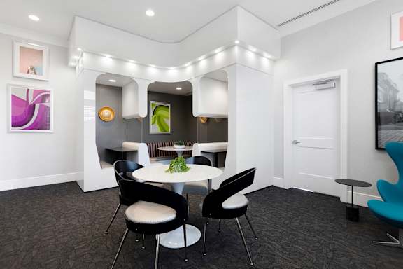 A modern dining room with a white table and black chairs.