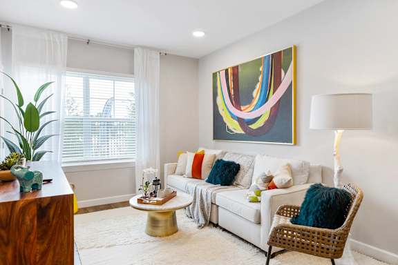 A living room with a white couch, a coffee table, a chair, and a painting on the wall.
