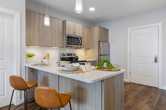 A kitchen with a white countertop and wooden cabinets.