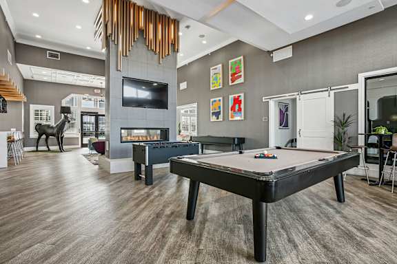 A pool table is in the middle of a room with a tv and a fireplace.