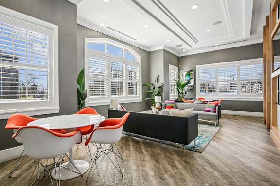 A modern dining room with a white table and orange chairs.