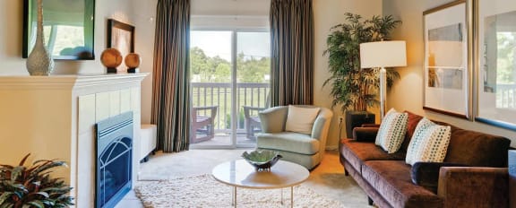 Living room Space with tan carpeting, burgundy couch, and fireplace with a white mantel at Chesapeake Ridge, North East, Maryland