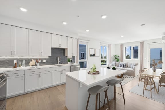 a white kitchen with a white island and a living room
