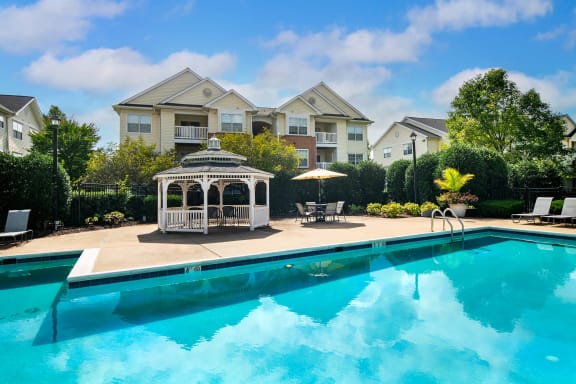 a swimming pool with a gazebo and a house in the background