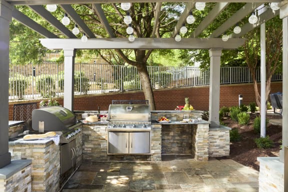 a outdoor kitchen with a grill and a pergola