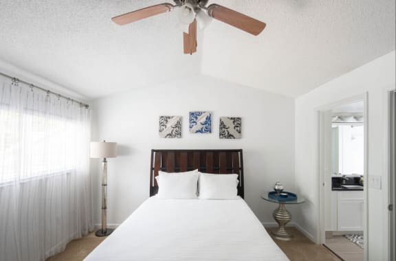 a bedroom with a large white bed and a ceiling fan
