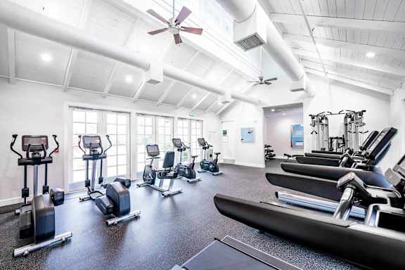 A gym with treadmills, elliptical machines, and other exercise equipment.