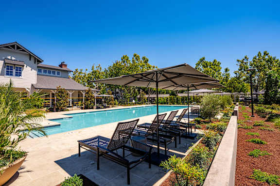 A pool area with lounge chairs and umbrellas.