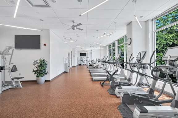 A gym with treadmills and a television on the wall.