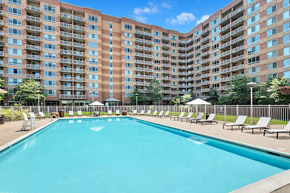 A large swimming pool in front of a multi-story apartment building.