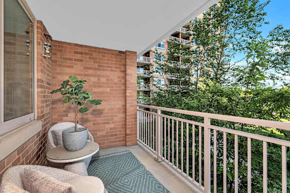 A balcony with a potted plant, a chair, and a table.
