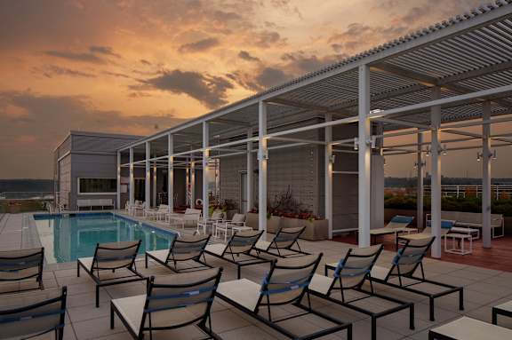 A poolside area with chairs and a building in the background.