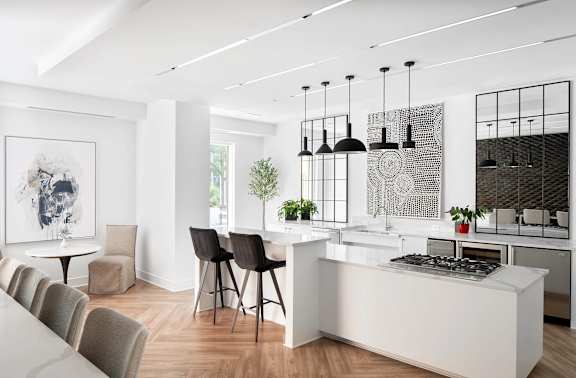 A modern kitchen with a white island and black chairs.