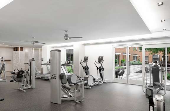 A gym with a variety of exercise equipment including treadmills, stationary bikes, and weight machines.