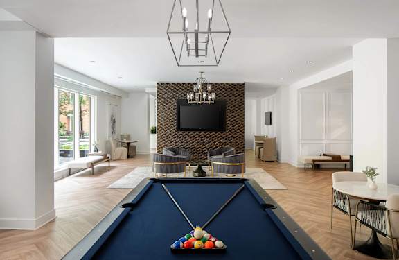 A pool table with a TV mounted on the wall in the background.
