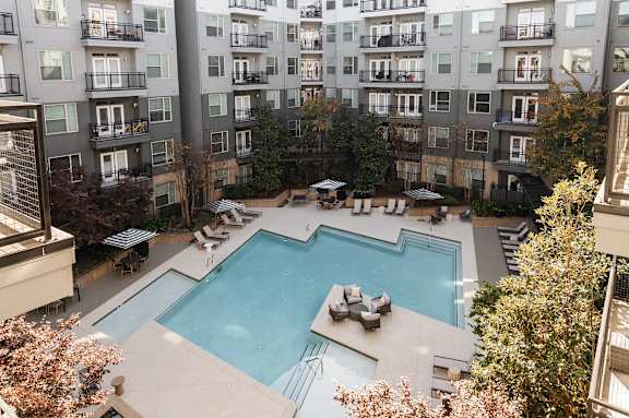A large swimming pool surrounded by lounge chairs and trees.