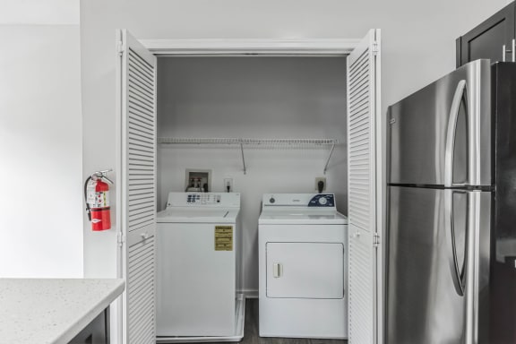a white laundry room with two washes and a refrigerator