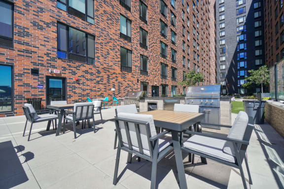 a patio with tables and chairs and a grill