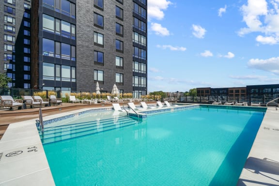 a swimming pool with chaise lounge chairs and a building in the background