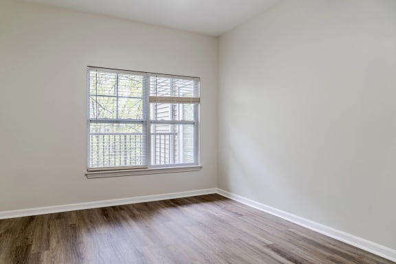 a bedroom with white walls and a window and wood floors