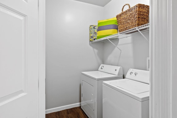 a laundry room with a washer and dryer and a basket on a shelf