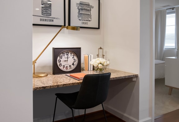 a desk with a clock and a chair in a room