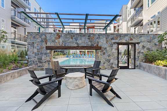 A patio with a stone wall and a hot tub.