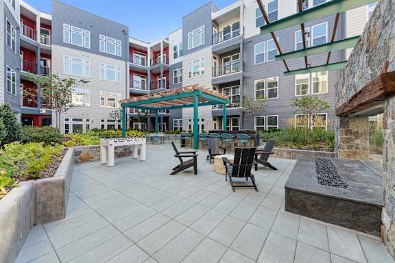 A patio area with a table and chairs is surrounded by apartment buildings.